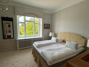 A bedroom with two beds, a window with a view, a radiator, and a lamp. - Aaroesund Badehotel (Haderslev)