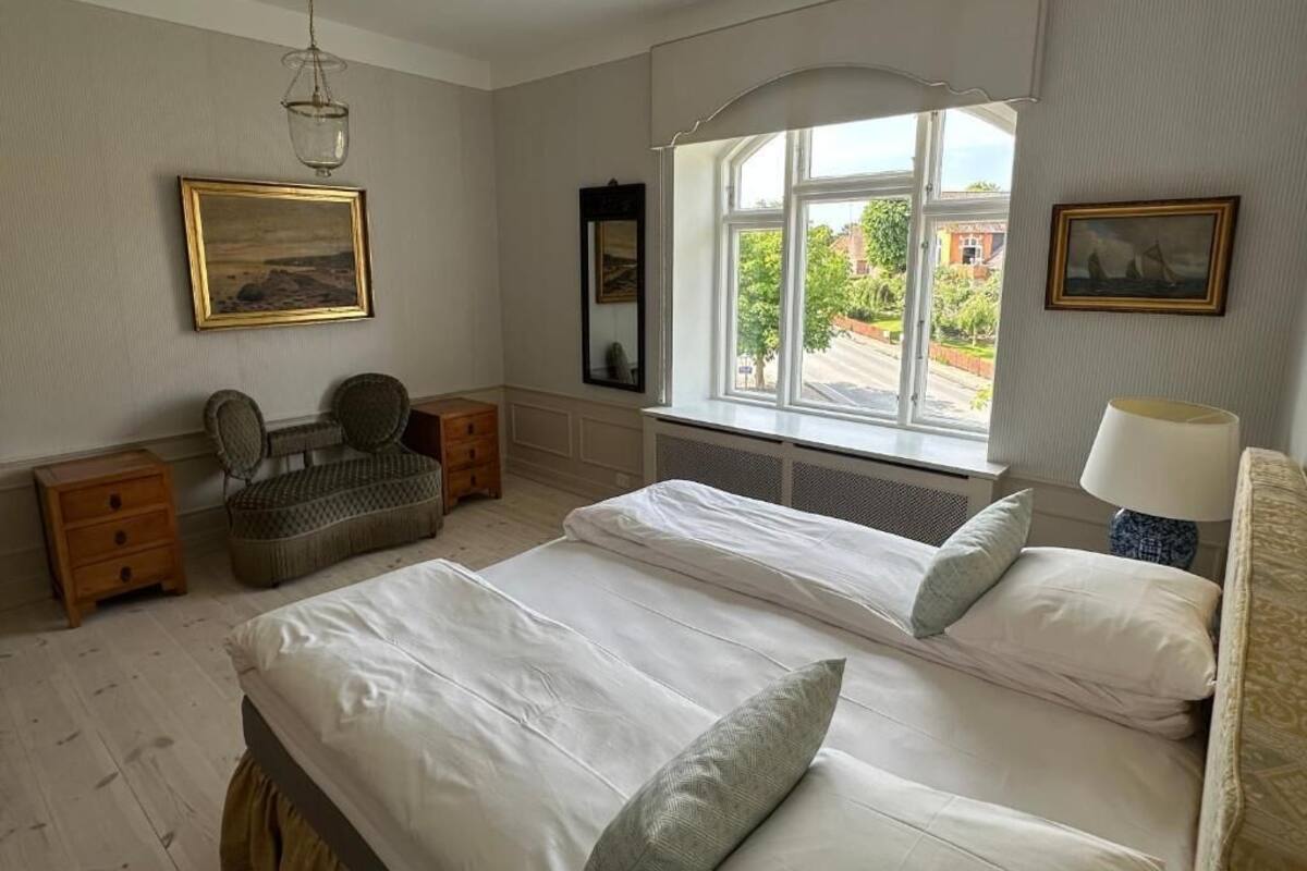 Un dormitorio con dos camas, una ventana con vistas, una lámpara colgante y una silla.