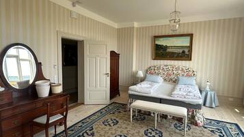 A bedroom with a bed, a dresser, a mirror, a bench, and a painting on the wall.