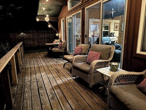Une terrasse extérieure aménagée avec des meubles en osier et une table en bois, donnant sur un jardin.