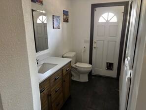 A bathroom with a white sink, wooden cabinet, and a toilet. - Furnished Studio with washer and dryer, and pool! (Ukiah)