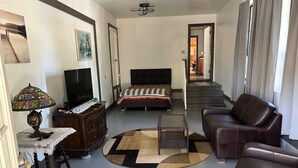 A living room with a bed, a sofa, a TV, a lamp, and a staircase leading to another room. - Furnished Studio with washer and dryer, and pool! (Ukiah)