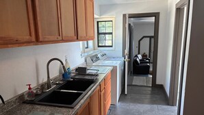 A kitchen with granite countertops, wooden cabinets, a stainless steel sink, and a built-in oven. - Furnished Studio with washer and dryer, and pool! (Ukiah)