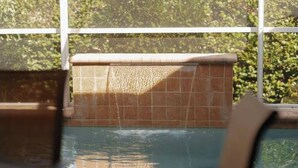 Ein Poolbereich mit gefliesten Wänden und Blick auf Grünfläche.