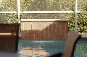 A pool area with tiled walls and a view of greenery outside.