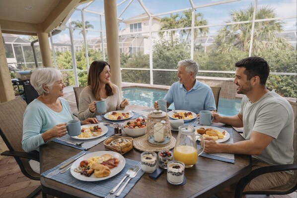 A group of people enjoying breakfast at a table with a view of a swimming pool and palm trees.