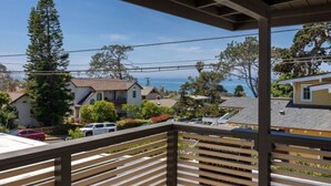 A residential area with houses, a view of the ocean, and a wooden balcony railing. - Charming Ocean View 2-bedroom apartment with AC in Del Mar! (Del Mar)