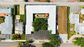 Vista aerea di un edificio con cortile centrale circondato da parcheggi e aree verdi.