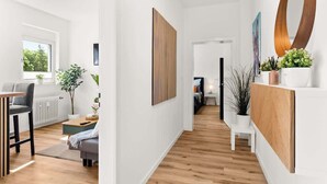 A modern hallway with wooden flooring, a grey sofa, a dining table with chairs, and a potted plant. - MOLA Apartments-Style & Design Wetter Ruhrgebiet (Wetter)