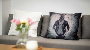 A sofa with two pillows, one plain and one with a graphic design, and a remote control on a wooden tray. - MOLA Apartments-Style & Design Wetter Ruhrgebiet (Wetter)