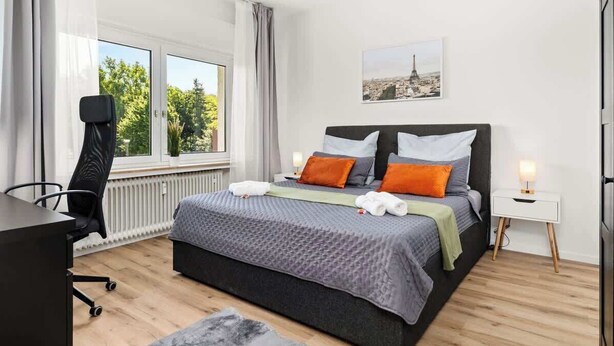 A modern bedroom with a large bed, a desk, and a chair. - MOLA Apartments-Style & Design Wetter Ruhrgebiet (Wetter)