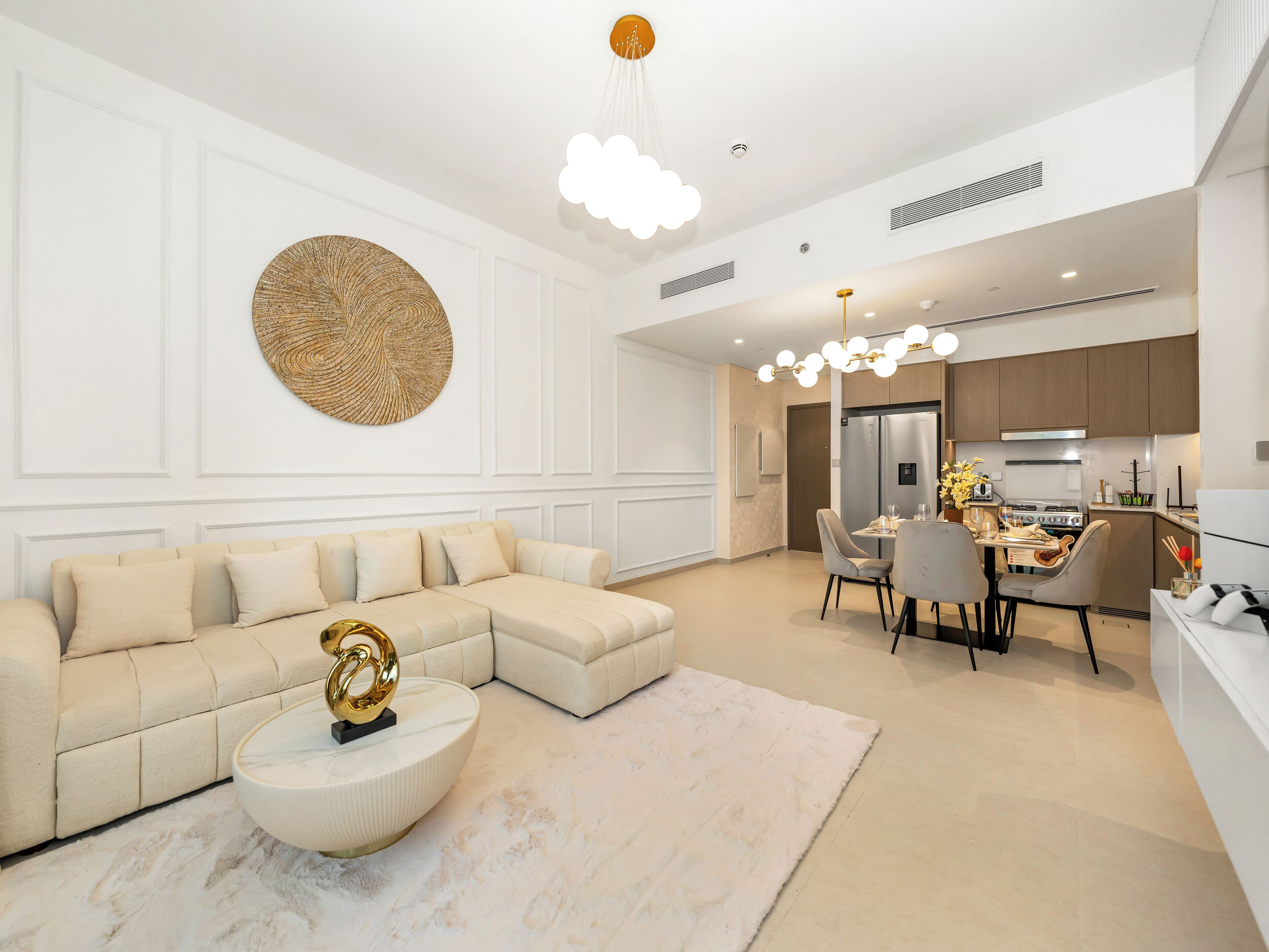 A modern living room with a sectional sofa, a coffee table, and a dining area with a chandelier.