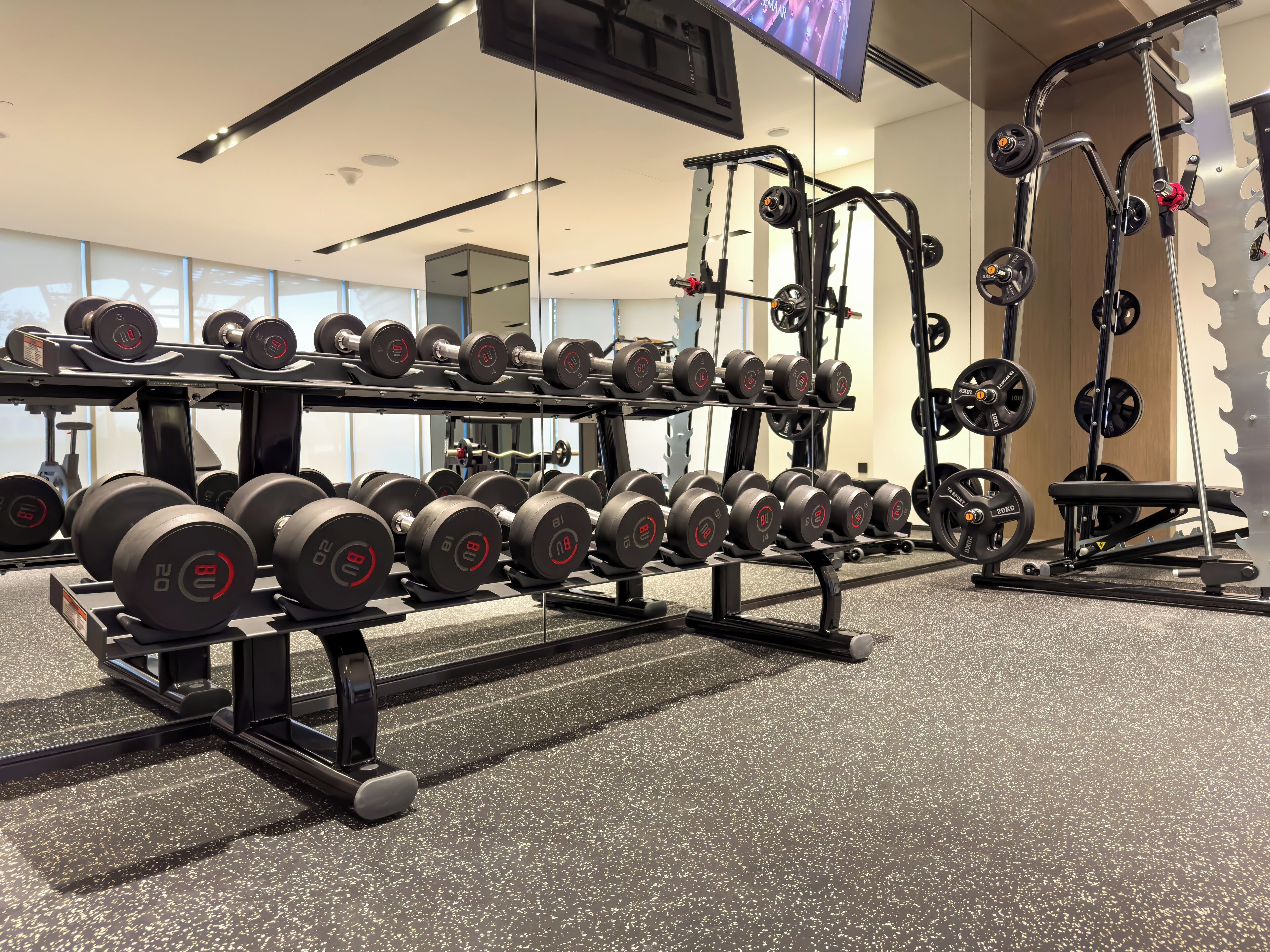 Une salle de sport équipée de matériel de musculation, notamment des haltères et des barres.