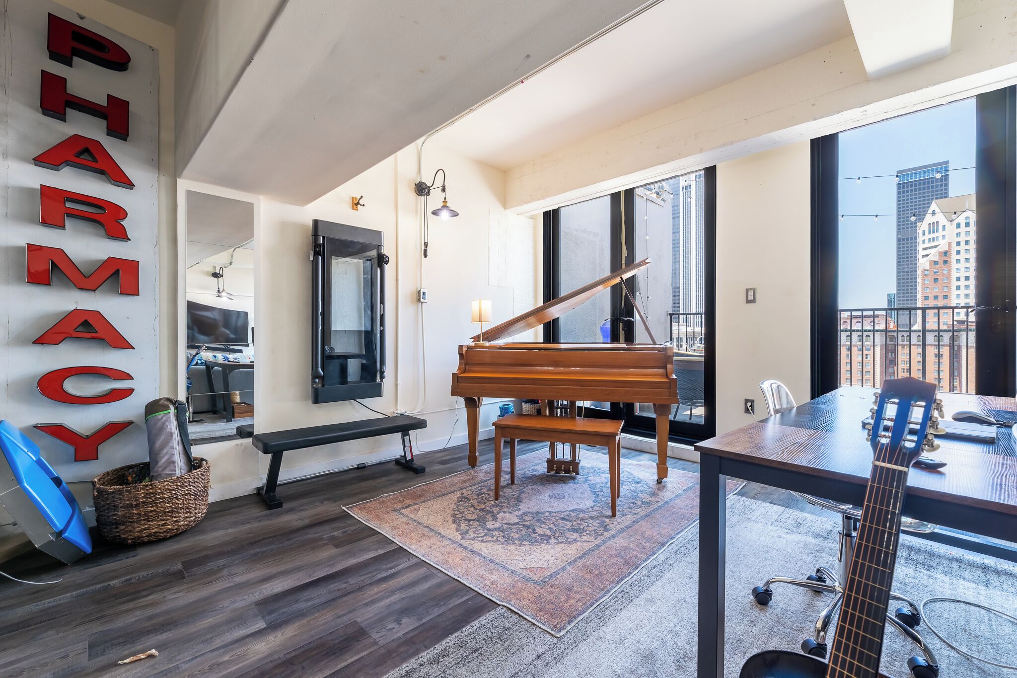 Een ruime kamer met een vleugelpiano, een gitaar en een groot raam met uitzicht over de stad.