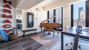 A spacious room with a grand piano, a guitar, and a large window offering a city view. - Sun-Soaked Urban-Chic Retreat in DTLA (Los Angeles)