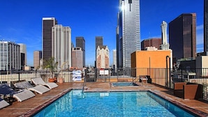 A rooftop pool with city skyline views, surrounded by high-rise buildings and a prominent tower. - Sun-Soaked Urban-Chic Retreat in DTLA (Los Angeles)