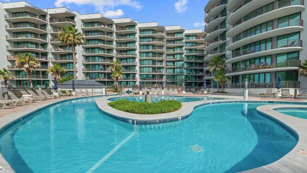Ein modernes Hotel mit mehreren Balkonen, einem zentral gelegenen Pool und gemütlichen Lounges.