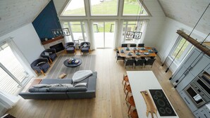 A spacious living area with a large sofa, a dining table, and a kitchen with modern appliances. - Muskoka 5BR Lakefront Cottage · Doe Lake · Sleeps 12+ · Pet-friendly · 4 Season (Gravenhurst)