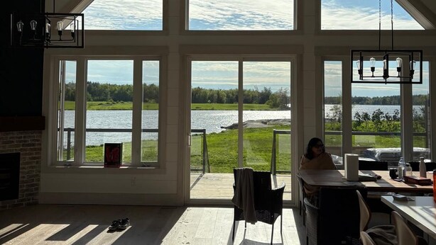 A spacious room with large windows offering a view of a lake and greenery. - Muskoka 5BR Lakefront Cottage · Doe Lake · Sleeps 12+ · Pet-friendly · 4 Season (Gravenhurst)
