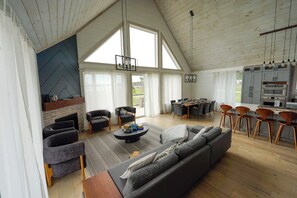 Un amplio salón con chimenea, muebles modernos y una cocina con taburetes de bar.