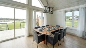 A dining area with a table set for six, large windows, and a view of a lake. - Muskoka 5BR Lakefront Cottage · Doe Lake · Sleeps 12+ · Pet-friendly · 4 Season (Gravenhurst)