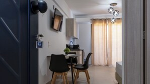 A modern, well-lit room with a dining area, a bed, and a kitchen area. - NS Apartments Nydri (Lefkada)