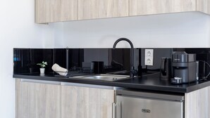 A modern kitchen with a black countertop, stainless steel appliances, and wooden cabinets. - NS Apartments Nydri (Lefkada)
