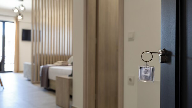A modern hotel room with a bed, bedside table, and a keychain with a number. - NS Apartments Nydri (Lefkada)
