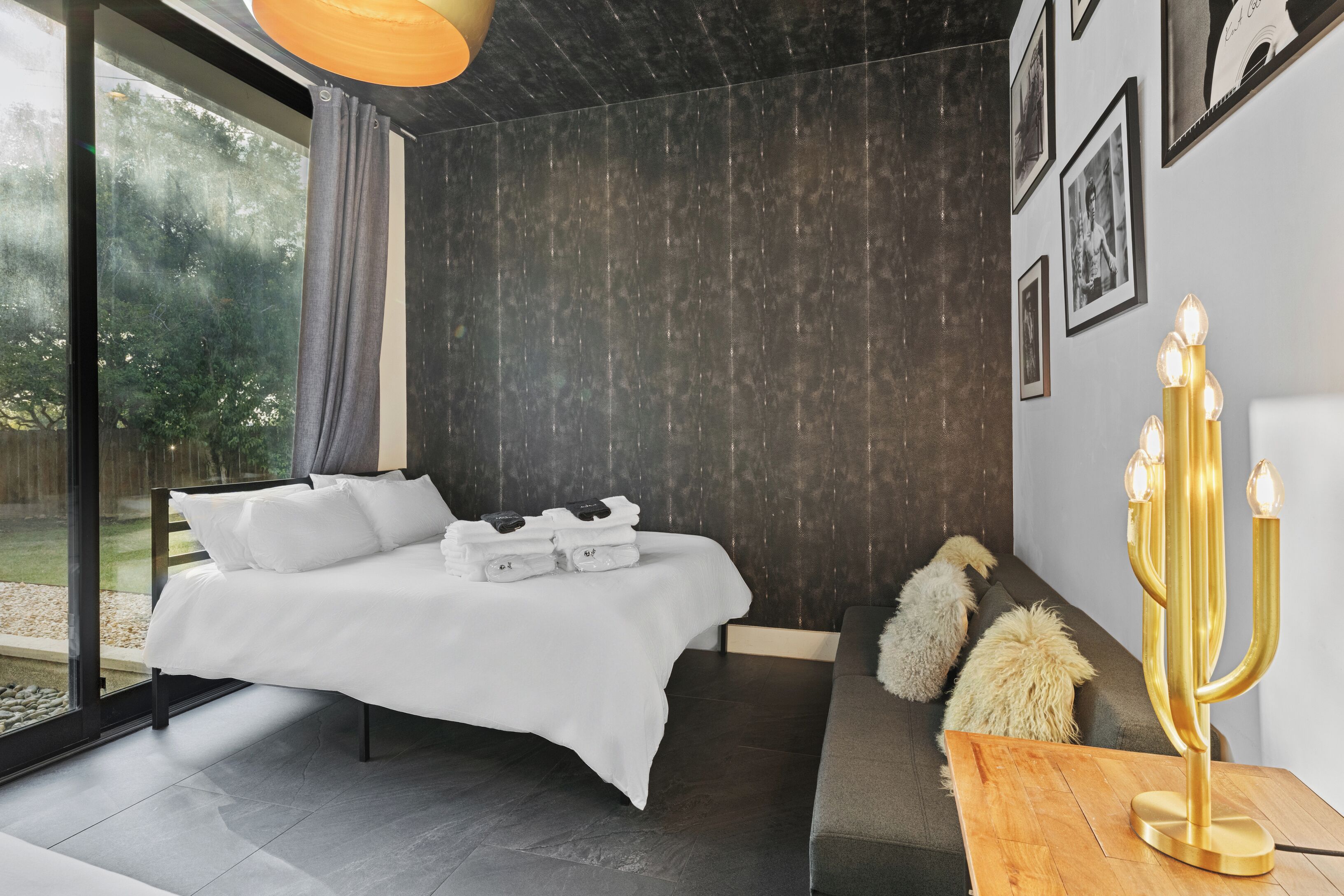 Un dormitorio moderno con una cama grande, un candelabro y vistas al verdor exterior.