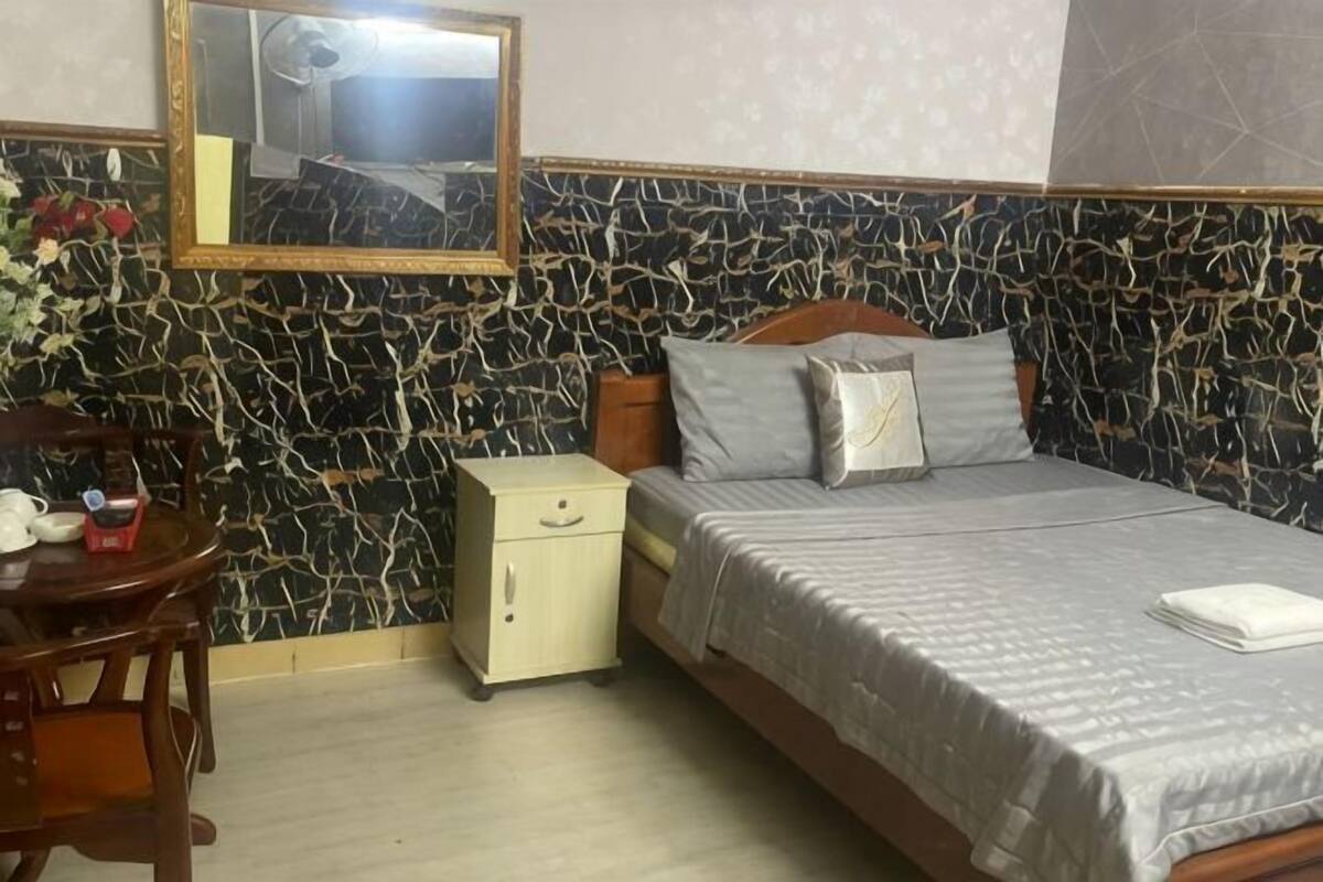 Une chambre à coucher avec un lit, une table de chevet, une commode et un miroir au mur.
