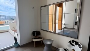 A modern bathroom with a large mirror, a toilet, a sink, and a chair. - Lagoon beach white 311 (La Serena)