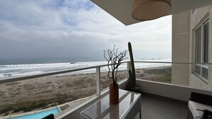 Ein Balkon mit Blick auf das Meer, einem Kaktus und einem Tisch mit Glasplatte.