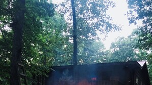 A stone fire pit with a fire burning in the center, surrounded by a stone patio.
