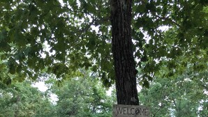 A wooden cabin with a 'WELCOME' sign, a porch, and a small deck.
