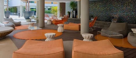 A modern lounge area with orange seating, white tables, and unique spherical ceiling lights.