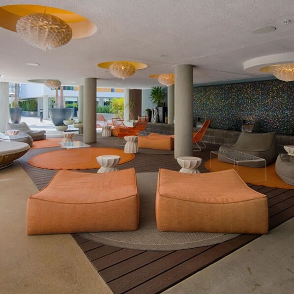 A modern lounge area with orange seating, white tables, and unique spherical ceiling lights.