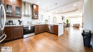 A modern kitchen with wooden cabinets, stainless steel appliances, and a central island. - Mayfield Manor-Hot Tub-KingBed-FireTable-BBQ-Wifi (Edmonton)