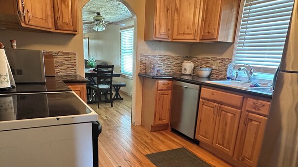 A kitchen with wooden cabinets, a dishwasher, a refrigerator, and a dining area with a table and chairs.