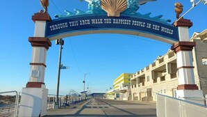 Un paseo marítimo que lleva a un edificio con un letrero que dice: 'Bajo este arco entran las personas más felices del mundo'.