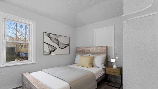 Un dormitorio con cama, mesita de noche y ventana.