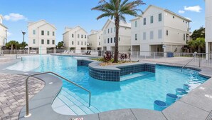 A swimming pool with a palm tree and lounge chairs, surrounded by white buildings with multiple windows. - Dreamy, Accessible Family Home for 12 (Orange Beach)