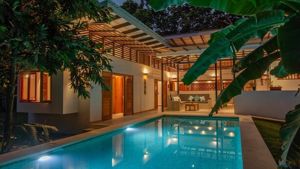 Una casa moderna con piscina, fachada de madera y un patio cubierto.