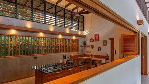 Una cocina moderna con una isla central, muebles de madera y vistas al exterior a través de un ventanal con celosías.