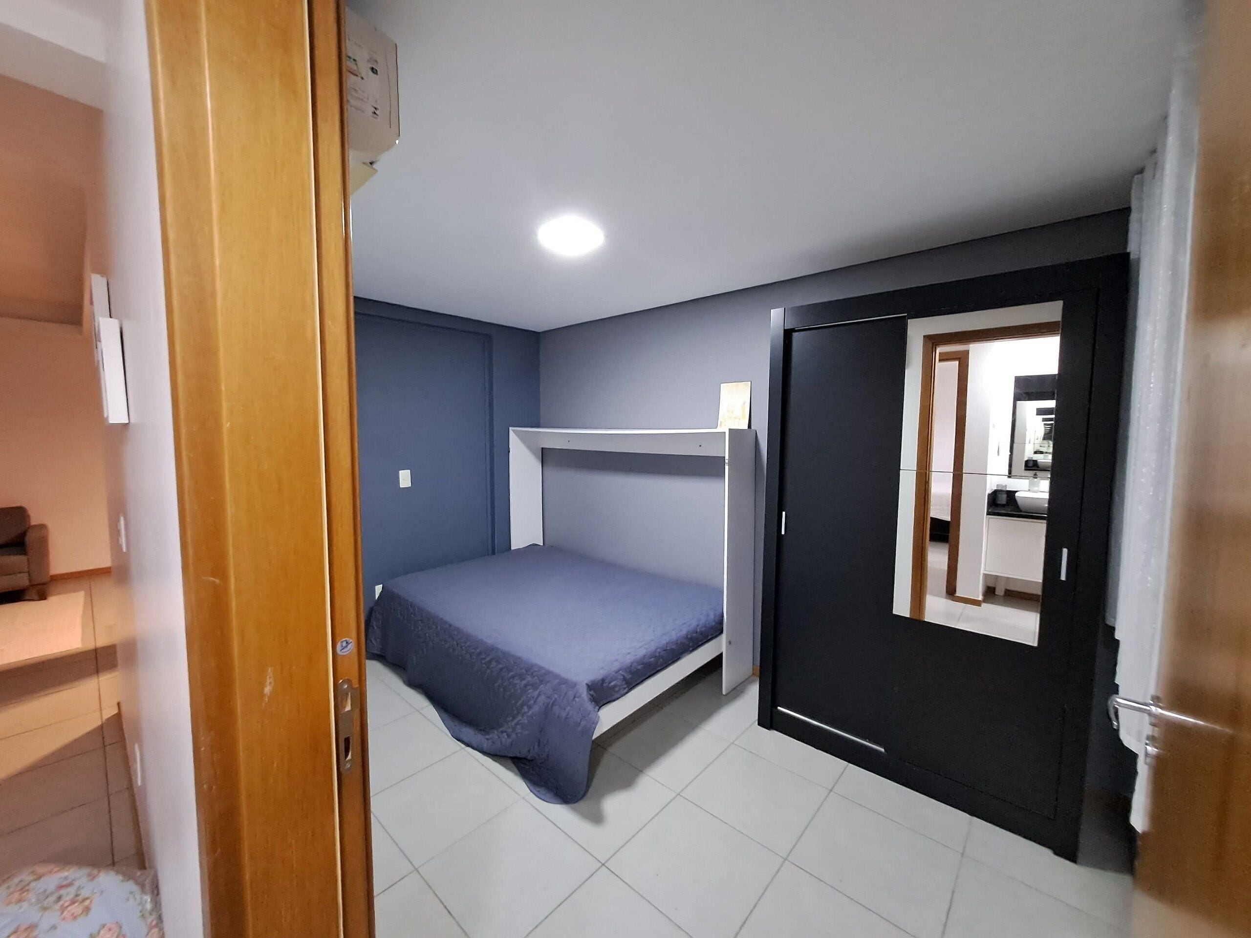 A compact room with a bunk bed, a small desk, and a bathroom visible through an open door.