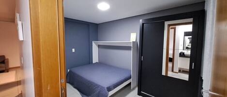 A compact room with a bunk bed, a small desk, and a bathroom visible through an open door.