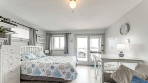 Ein Schlafzimmer mit Bett, Kommode und Blick ins Freie.
