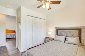Um quarto com cama, mesa de cabeceira e ventilador de teto.