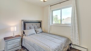 Una camera da letto con un letto, un comodino, una ventola a soffitto e una finestra con tende.