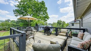 Eine Terrasse mit Gartenmöbeln, einem Grill und einem großen Sonnenschirm.