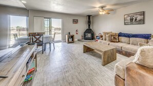 Een ruime woonkamer met een open haard, een houten salontafel, een bank en uitzicht op de omgeving.